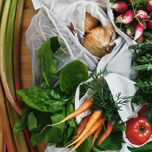 up close of groceries in bag including carrots, onions, tomatoes
